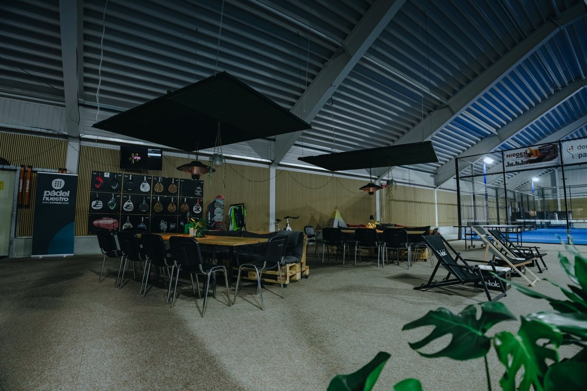 The lounge at Padel Planet with tables, chairs and a view of the courts