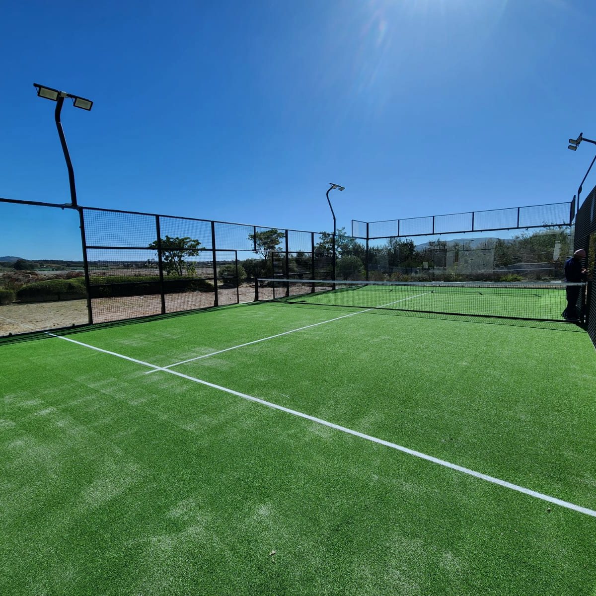 Grüner Padel-Kunstrasen auf einem fertigen Außencourt, frisch verlegte weiße Linien